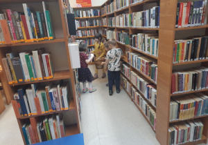 Dzieci szukają jajek na półkach z książkami